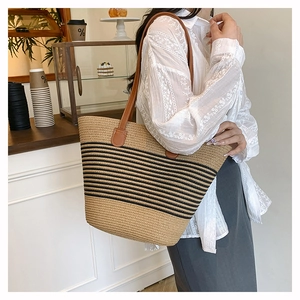 Détail du sac cabas tissé à rayures avec anses en cuir porté par un mannequin
