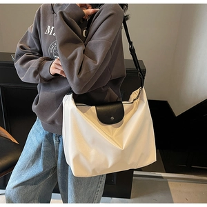 Detail of white nylon tote bag with black leather flap and wide adjustable strap