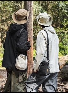 Detail view of nylon crossbody bags with drawstrings and side labels in outdoor forest