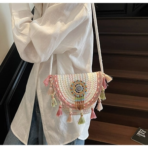 Macro view of bohemian woven bag with colorful tassels, beads, and geometric embroidery