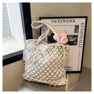 Détail du sac panier blanc tissé main avec nœud en dentelle et breloque perle