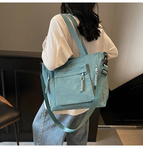Detail showing high-capacity teal nylon tote bag with multi-pockets and woven zip pulls