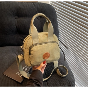 Details einer hellgrünen Nylon-Umhängetasche mit Reißverschlussfach und rundem Logo