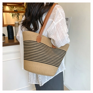Détail du sac cabas tissé à rayures avec bandoulières en cuir marron porté à l'épaule