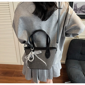Détail d'un sac seau tissé avec bandoulière en cuir et charm perle et dentelle