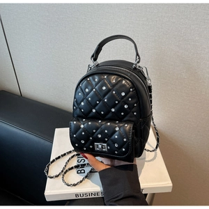 Detail of black quilted leather mini backpack with sparkling white rhinestones and chain