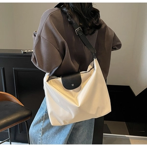 Close-up of cream nylon tote bag with black leather flap and adjustable strap details