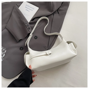 Minimalist white shoulder bag detail showing side pleated pocket and glossy PU texture