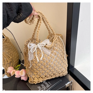 Détail du sac à main tissé beige avec nœud en dentelle blanche et chaîne en perles fines