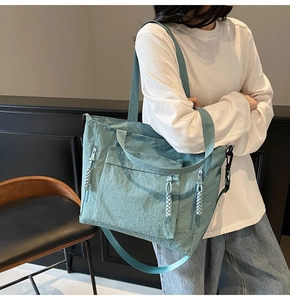 Close-up of teal nylon tote bag with adjustable strap and textured front pocket detail