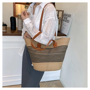 Détail du sac cabas en paille tissée avec rayures noires et bandoulières en cuir marron