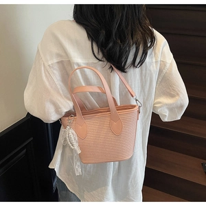 Détail du sac en paille tissée rose avec breloque en dentelle perlée et lanière en cuir