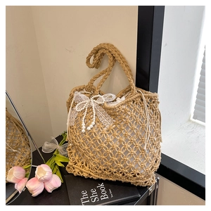 Détail du sac cabas tissé kaki avec nœud en dentelle blanche et breloque en perles
