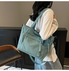 Detailed back view of a teal nylon tote bag with textured surface and woven zipper pullers