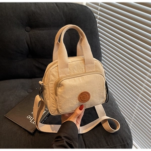 Detailansicht der beige Nylontasche mit Vordertasche und braunem Lederlogo-Aufnäher