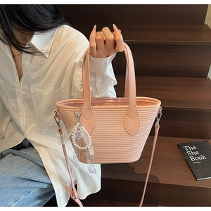 Détail du sac cabas en paille rose avec breloque en perles et poignée en cuir d'été