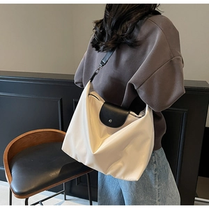 Close-up of cream nylon tote bag with black leather flap and metallic snap button