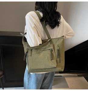 Detail view of large olive green nylon tote bag featuring hand-woven rope zippers and flap pocket