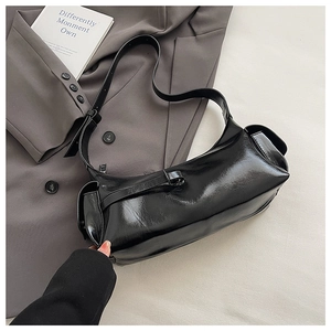 Close-up of a glossy black minimalist bowling bag with functional side flap pockets