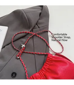 Détail du sac nuage rouge plissé avec texture litchi et chaîne sur un blazer gris