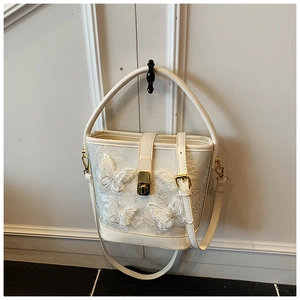 Détail du sac seau blanc avec broderie papillon 3D et fermoir en métal doré