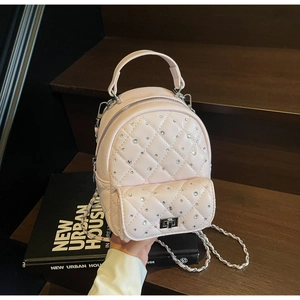 Close-up of pink quilted mini backpack with rhinestone decor and silver chain strap