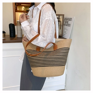 Détail d'un grand sac cabas tissé à rayures avec des anses en cuir marron sur un mannequin