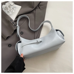 Detail of light blue faux leather pillow bag with adjustable strap and side pockets