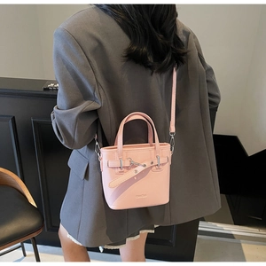 Dettaglio borsa a secchiello in pelle rosa chiaro con trama litchi su blazer grigio