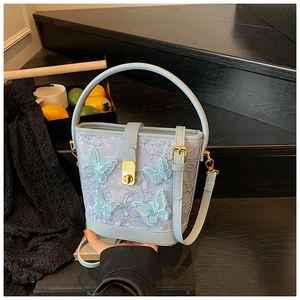 Détail d'un sac seau en dentelle bleu clair avec broderies papillons et fermoir doré