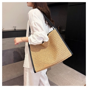 Grand sac cabas en paille avec bordure en cuir noir porté à l'épaule pour femme