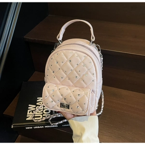 Detail view of pink quilted mini backpack with rhinestone accents on wooden stairs