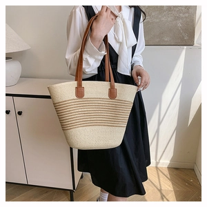 Détail de la texture tressée ivoire et marron d'un sac cabas d'été avec anses en cuir