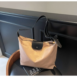 Detail of elegant nylon tote bag featuring black leather flap and metal snap closure