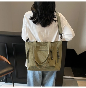 Olive green nylon tote bag showing a side view of its large capacity and pocket details