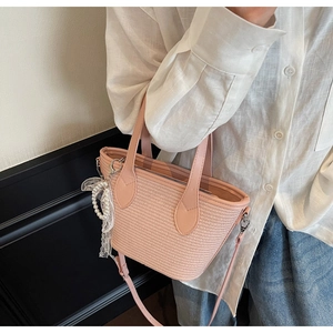 Détail du sac cabas en paille rose avec breloque en perles et poignées en cuir