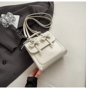 Détail du sac en similicuir crème avec chaîne en perles et nœud décoratif