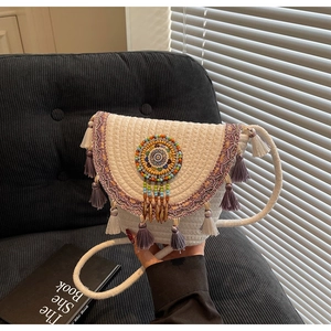 Detail of bohemian woven crossbody bag with purple fringes and beaded embroidery