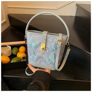 Détail du sac seau bleu clair avec broderie papillon 3D et ornements en métal doré