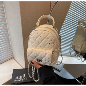 Close-up of beige quilted mini backpack with rhinestone details and silver chain strap