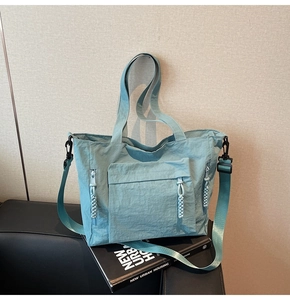 Detailed close-up of large capacity nylon tote bag with front pocket and woven zipper pulls