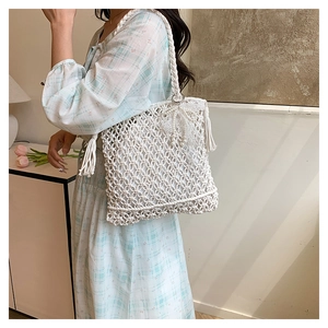 Détail d'un sac cabas tissé blanc ajouré avec un grand nœud en dentelle et perles