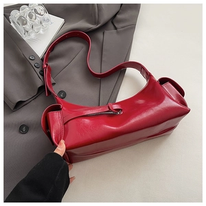 Macro detail of red glossy leather shoulder bag with side pocket and adjustable strap