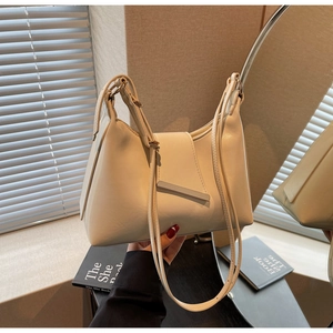 Nahaufnahme der minimalistischen beigen Ledertasche mit Metalldetail und verstellbarem Gurt