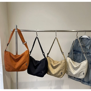Four crescent canvas tote bags in burnt orange, black, beige, and cream colors