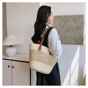 Détail d'un grand sac fourre-tout en paille tissée avec rayures et anses en cuir