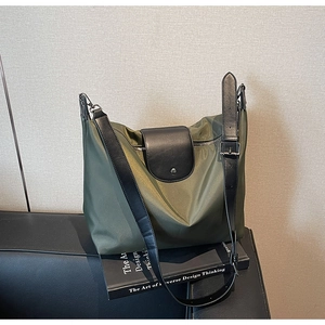Detail of dark green oxford tote bag on a black leather sofa with a design book