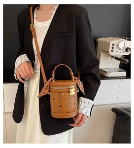 Detail of vintage brown cylinder bag with bear charm and silk scarf handle accent