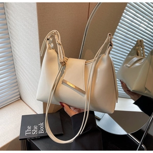 Detail einer cremefarbenen Ledertasche mit Goldleiste und Spiegelreflexion im Licht