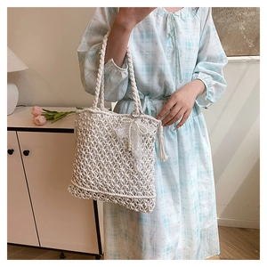 Détail du sac de plage au crochet beige avec nœud en dentelle et perles nacrées